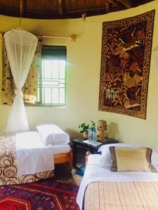 Twin beds under a mosquito net in the Coffee Cottage, with a wall hanging above.