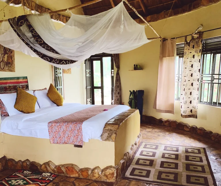 A Nyore cottage interior with a high thatched roof, timber beams, stone floors and patterned fabrics.