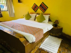 The Mango Cottage bedroom with a king-size bed, kitenge cushions and stone floor.