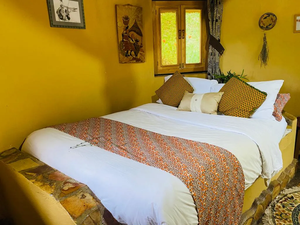 The Peanut Cottage bedroom with a double bed, printed throw and warm yellow walls.