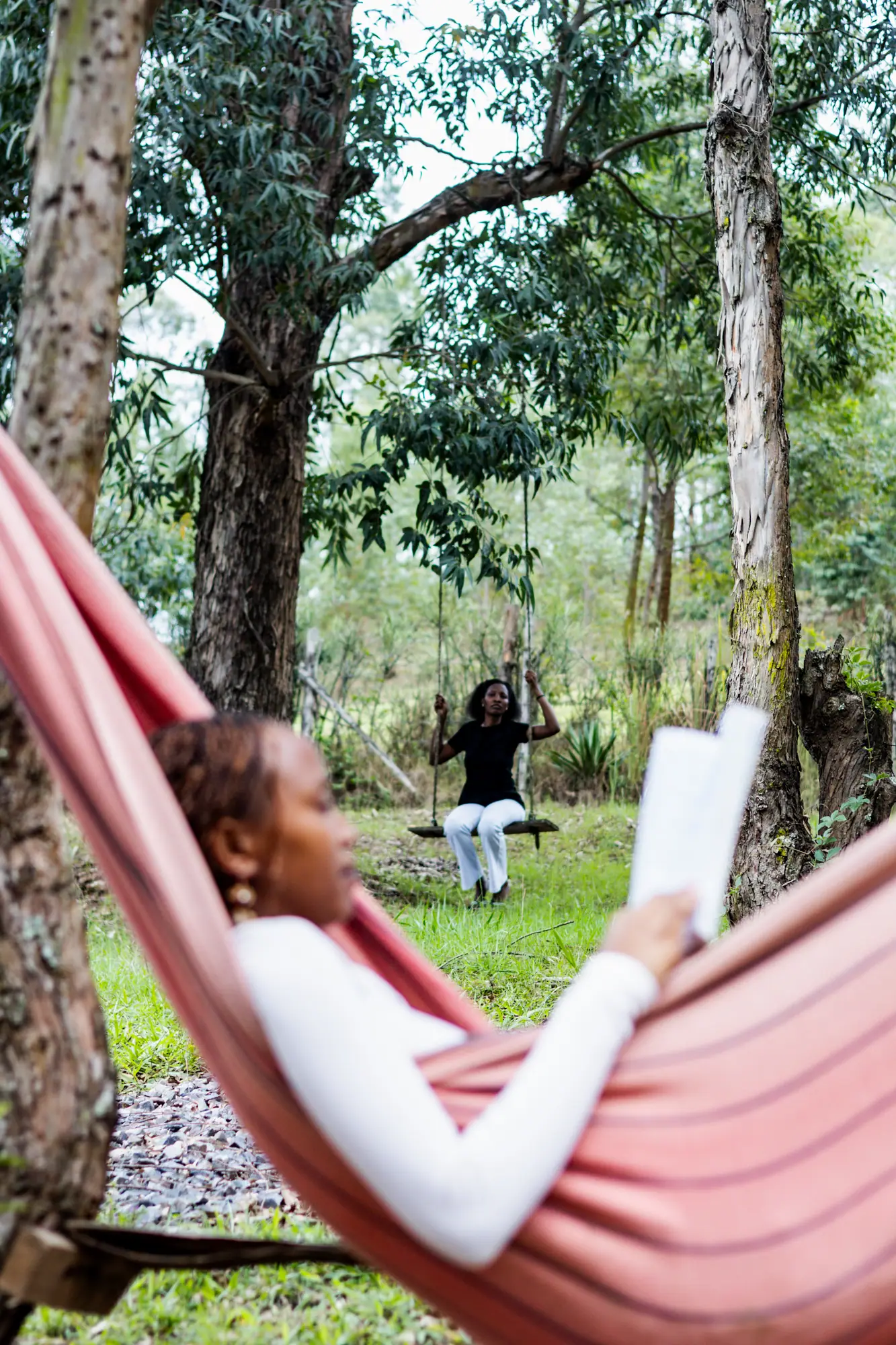 A guest reads in a hammock among the trees.