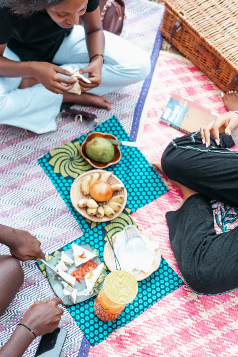 Guests share fruit and snacks on a colourful picnic mat.