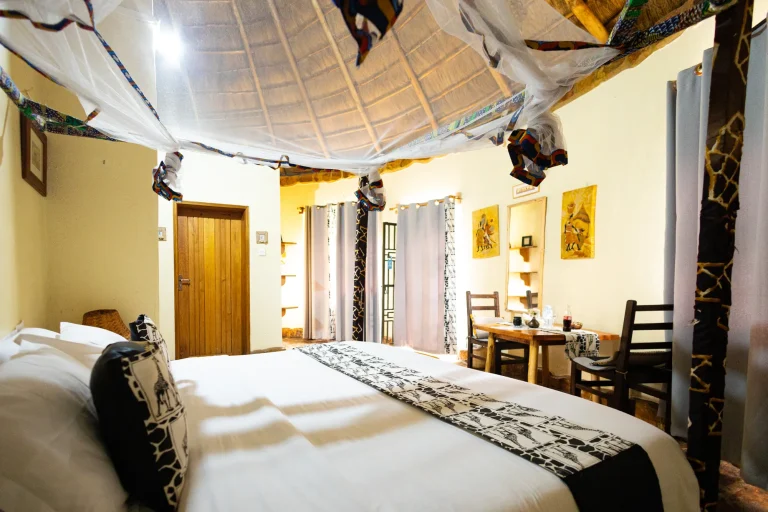 A cottage bedroom with a mosquito net, patterned bed runner and timber furniture.