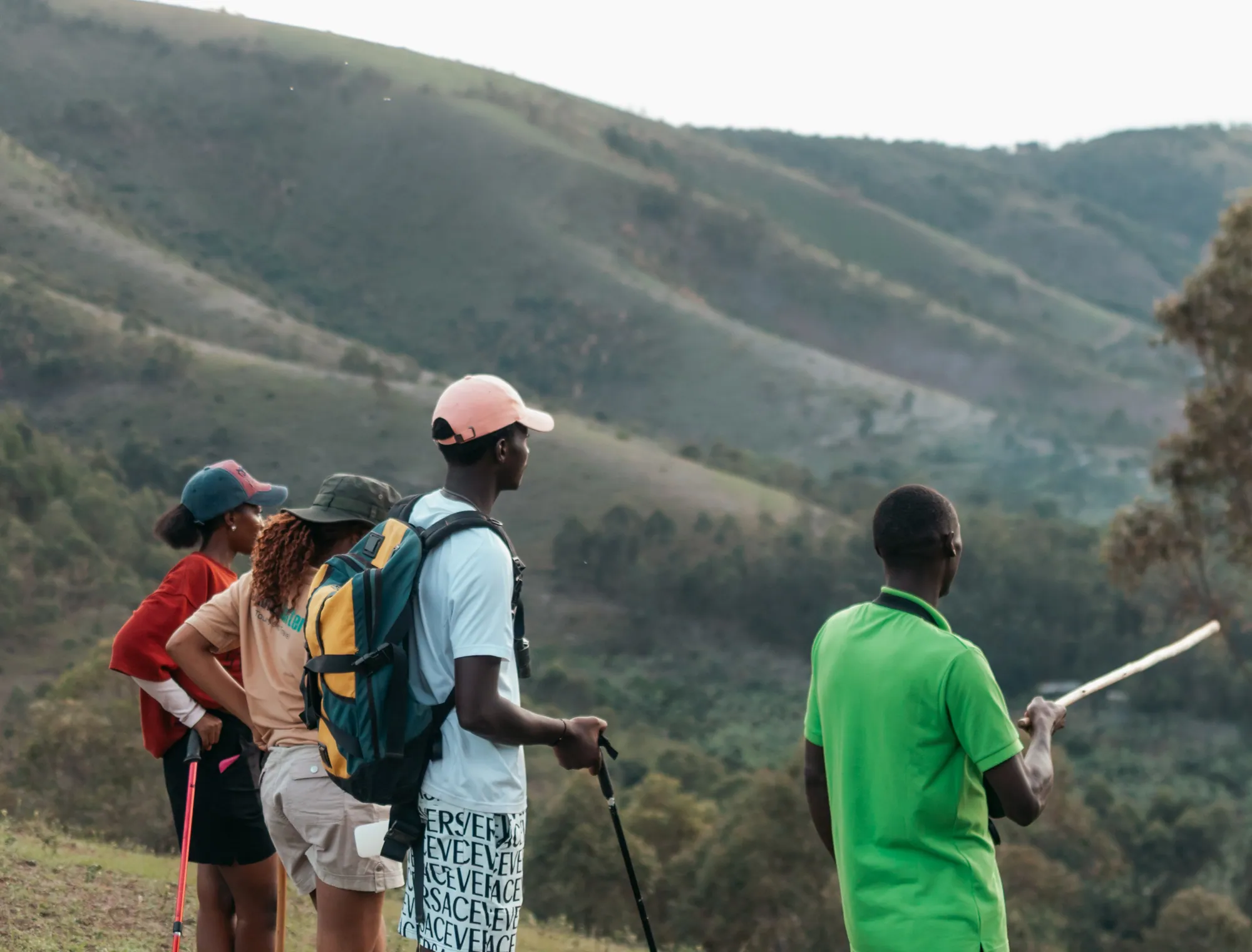 A walking guide points out the valley to a group of hikers on the hillside.
