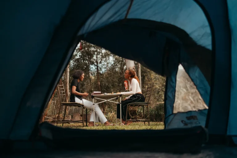 Guests sit at an outdoor table, viewed through an open tent doorway.