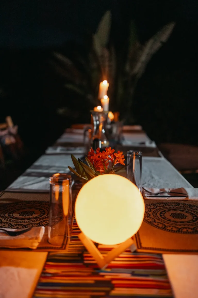 A long dinner table set with candles and a glowing lantern.