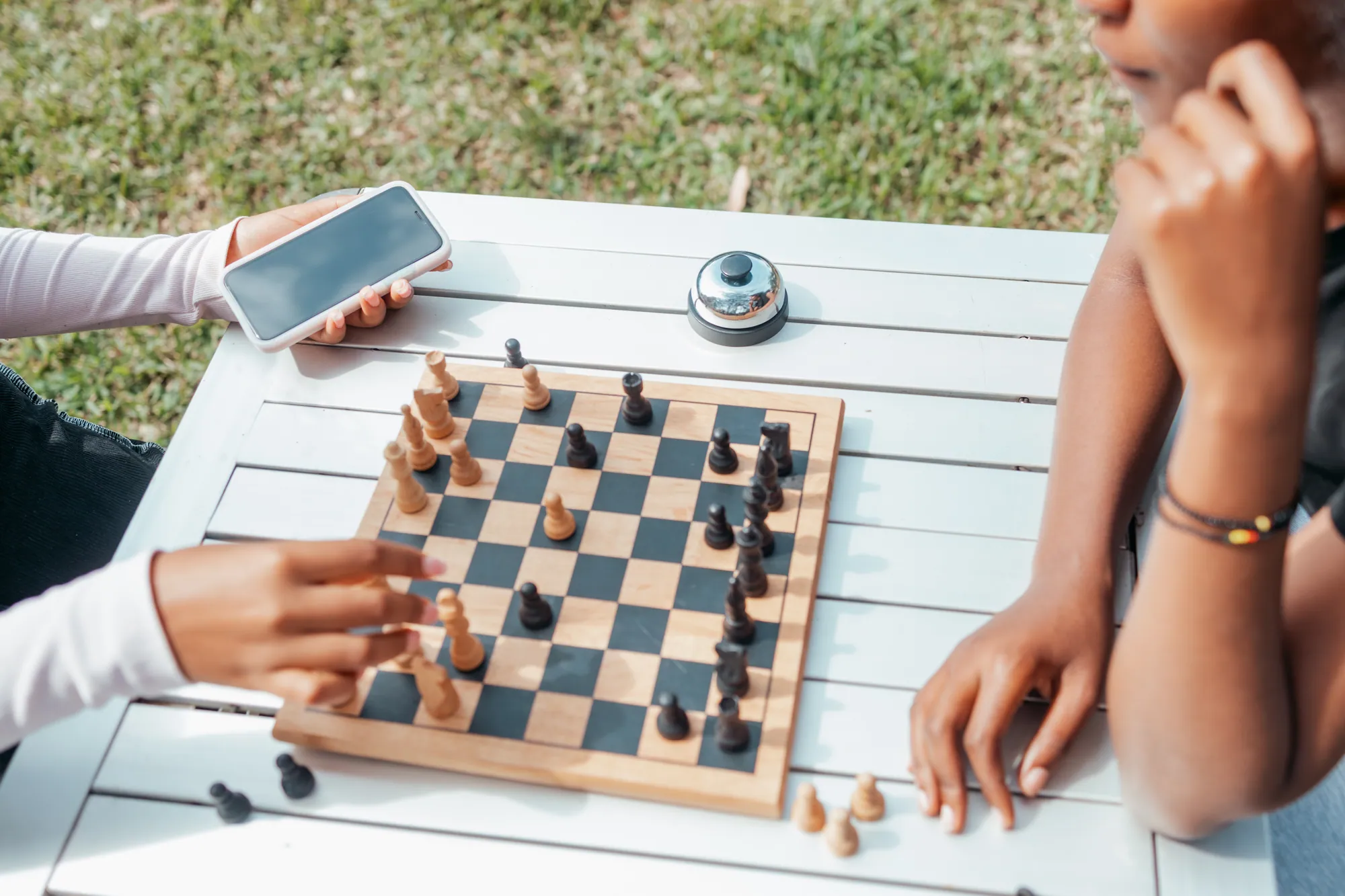 Two guests play chess on a garden table.