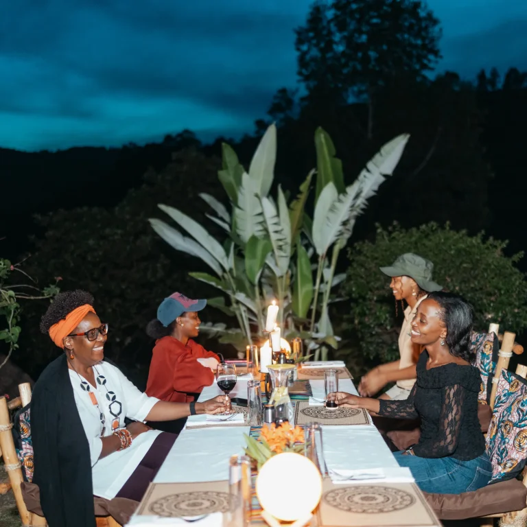 Guests share a candlelit dinner outdoors at dusk.