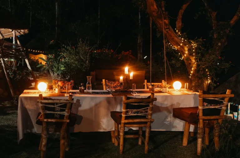 Outdoor dining tables lit for an evening meal in the gardens.