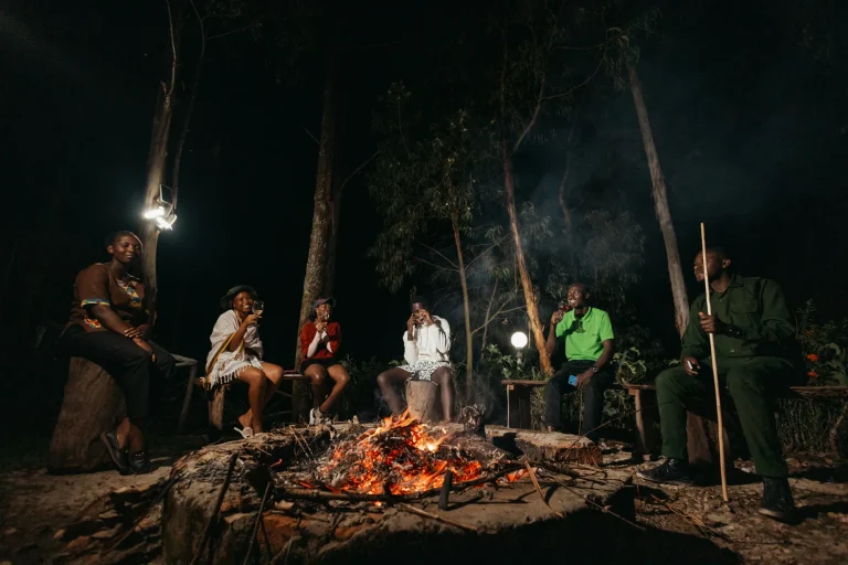 Guests gather around an outdoor bonfire at night.