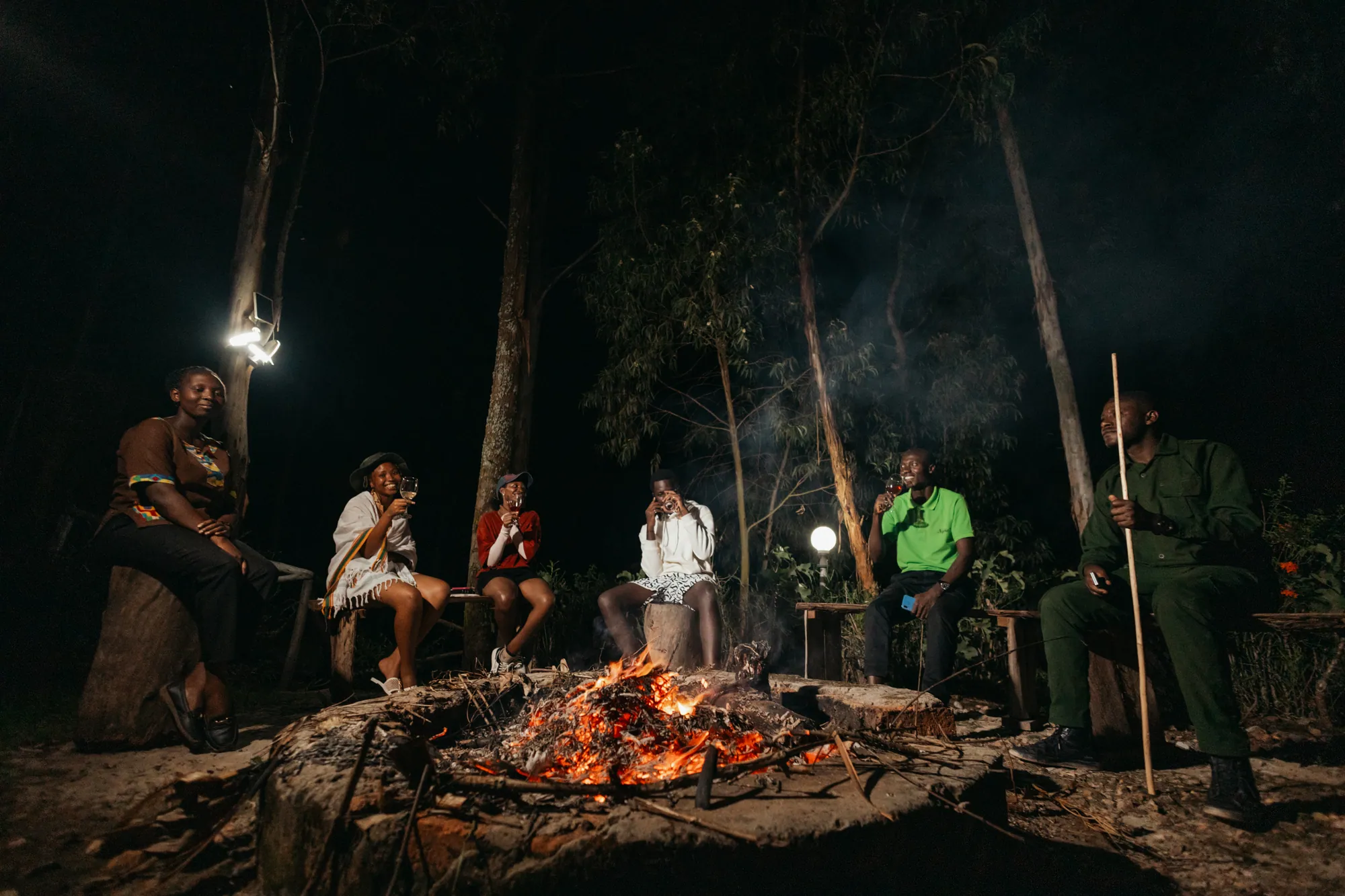 Guests gather around an outdoor bonfire at night.