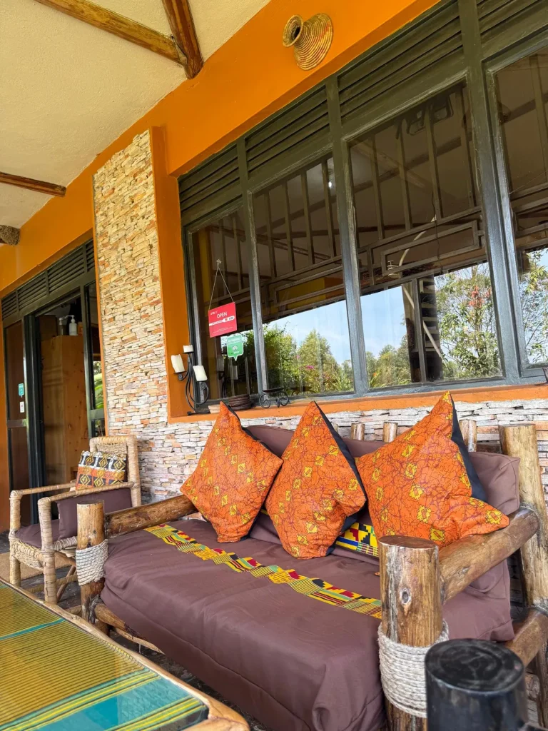 Nyore’s veranda with natural timber, ochre walls, patterned cushions and stonework.