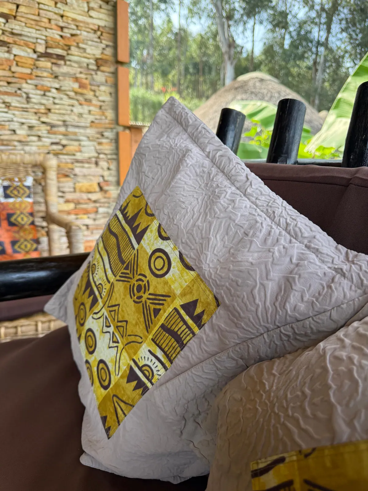 Geometric patterned cushions beside Nyore’s stone wall and timber veranda.